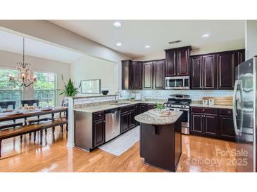 Modern kitchen featuring dark wood cabinets, granite countertops, and stainless steel appliances with hardwood flooring at 5056 Crandon Rd, Fort Mill, SC 29707