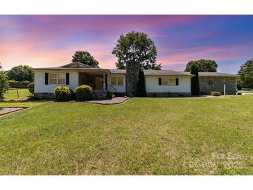 Charming one-story home featuring a manicured lawn and stone accents on the facade and chimney at 7430 Forney Hill Rd, Denver, NC 28037