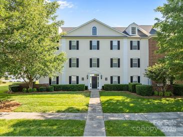 Attractive three-story condo with black shutters, manicured lawn, and lush green trees under a bright blue sky at 4024 Town Center Rd, Harrisburg, NC 28075