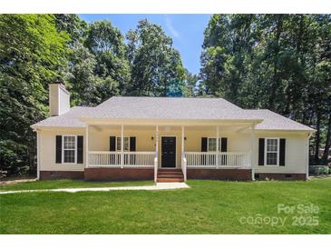 Charming single story home featuring a welcoming front porch, well-manicured lawn, and mature trees at 9000 Vagabond Rd, Charlotte, NC 28227