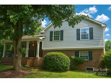 Charming two-story home featuring a covered front porch, lush landscaping, and a well-maintained lawn at 12431 Agate Ln, Pineville, NC 28134
