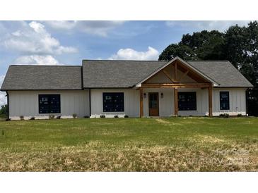 Charming home with white siding, dark framed windows and a wooden entry sitting on a spacious green lawn at 1389 Hartsoe Rd, Lincolnton, NC 28092