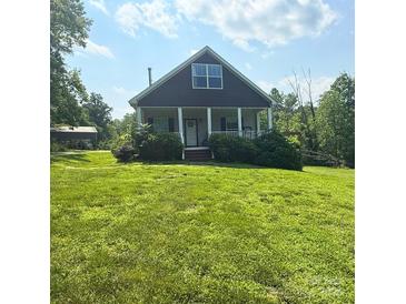 Charming home with a front porch, lush green lawn, and mature trees, offering a peaceful and inviting atmosphere at 3659 Vashti Rd, Taylorsville, NC 28681