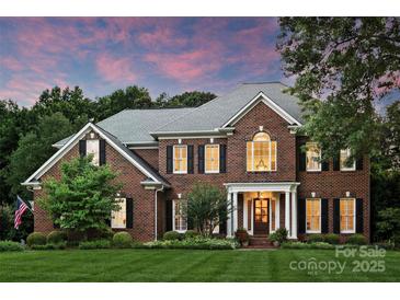 Elegant brick home showcasing manicured landscaping and a welcoming front porch, set against a colorful dusk sky at 159 Carsons Pl, Mooresville, NC 28117