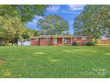 Charming one-story brick home with a well and a large green lawn under a sunny blue sky at 37156 Southside Rd, Albemarle, NC 28001