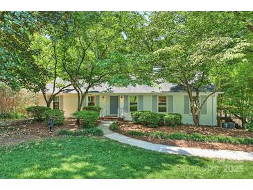 Charming one-story home with manicured lawn, inviting walkway, and mature trees providing ample shade at 6150 Rocky Falls Rd, Charlotte, NC 28211