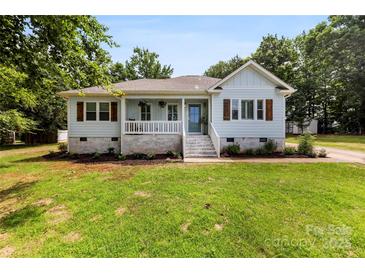 Charming single-story home featuring light blue siding, a welcoming front porch, and beautifully landscaped front yard at 8438 Henry Harris Rd, Fort Mill, SC 29707