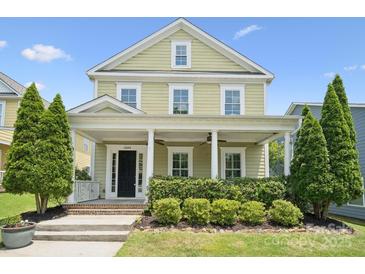 Charming two-story home with a welcoming front porch, manicured landscaping, and lush greenery at 12525 Druids Glen Dr, Pineville, NC 28134