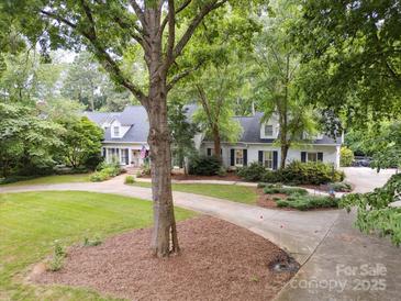 An exterior view of a beautiful home with mature landscaping and a circular driveway at 2032 Greenbrook Pkwy, Matthews, NC 28104
