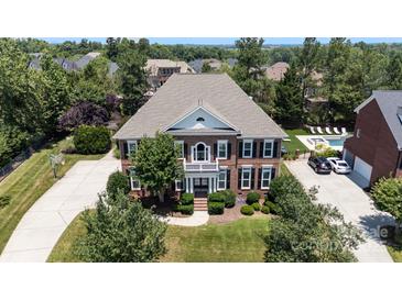 Stately brick home featuring a well-manicured lawn, mature trees, and an inviting front porch with columns at 11335 Wescott Hill Dr, Huntersville, NC 28078