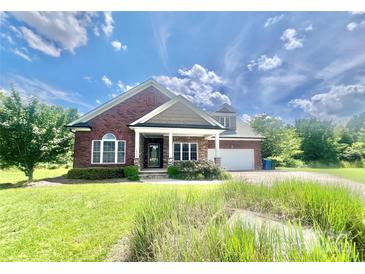 Charming red brick home with stone accents, covered porch, manicured lawn, and attached two-car garage at 1302 Devonmere Pl, Salisbury, NC 28144