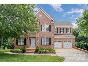 Charming two-story brick home featuring a well-manicured front yard and a three-car garage at 14746 Greenpoint Ln, Huntersville, NC 28078