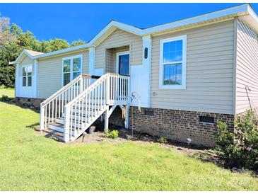 Charming manufactured home featuring a covered entry with white stairs and light beige siding on a sunny day at 4713 White Store Rd, Wingate, NC 28174