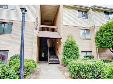 The exterior shows the front entrance to the condo with brick and surrounding green bushes at 4806 Spring Lake Dr # D, Charlotte, NC 28212