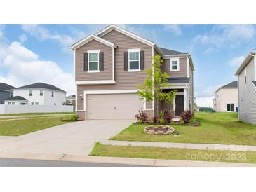 Two-story home featuring a two-car garage, tan siding, a manicured lawn and well-maintained landscaping at 1022 Jeffery Dean Ct, Albemarle, NC 28001