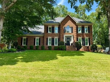 Stunning brick home with a large lawn, mature trees, and classic black shutters at 1140 Iverleigh Trl, Charlotte, NC 28270