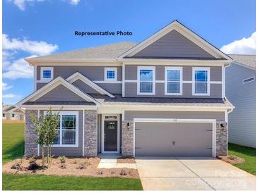 Charming two-story home featuring stone accents, a two-car garage, and a well-manicured lawn at 139 Asmodean Ln, Troutman, NC 28166