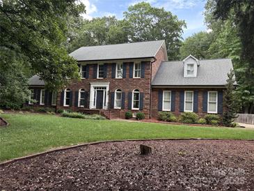 Elegant two-story brick home featuring a manicured lawn and black shutters for a classic, sophisticated look at 1545 Chadmore Nw Ln, Concord, NC 28027
