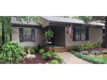 Inviting exterior featuring a charming entrance with well-manicured landscaping, an American flag, and a hanging fern at 353 Tall Oaks Trl, Fort Mill, SC 29715