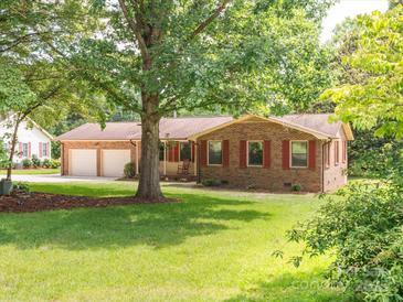 Charming single-story brick home with red shutters, attached two-car garage, mature trees, and a green lawn at 10728 Forest Dr, Matthews, NC 28105