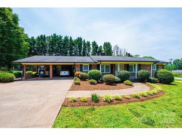 Charming brick home with well-manicured landscaping, inviting walkway, and attached carport at 1211 25Th Se St, Hickory, NC 28602