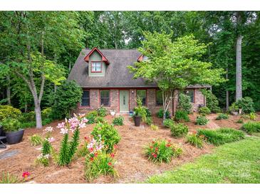 Charming brick home featuring dormers and a beautifully landscaped front yard with colorful flowers at 169 Primrose Ln, Statesville, NC 28625