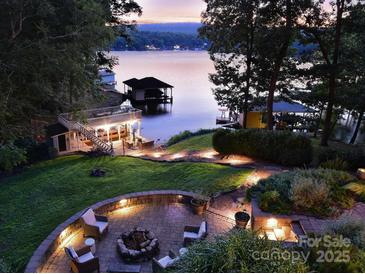 Inviting backyard with a stone patio, fire pit, and scenic lake views at sunset at 369 Skyland Ct, Mount Gilead, NC 27306