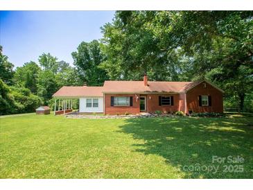 Charming red brick home with a spacious front yard, mature trees, and covered entrance at 7016 Tirzah Rd, Waxhaw, NC 28173