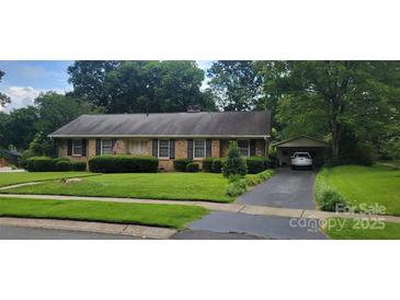 Charming brick home with mature landscaping and a convenient covered parking area at 7017 Knightswood Dr, Charlotte, NC 28226
