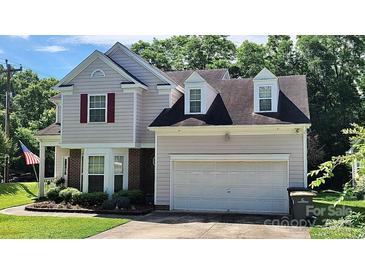 Charming two-story home with gray siding, red shutters, attached two car garage, and well-maintained landscaping at 1902 Stonewyck Ave, Kannapolis, NC 28081