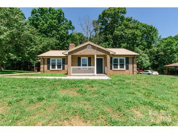 Charming brick home with a covered porch and front yard, surrounded by trees at 142 Single Oak Dr, Troutman, NC 28166