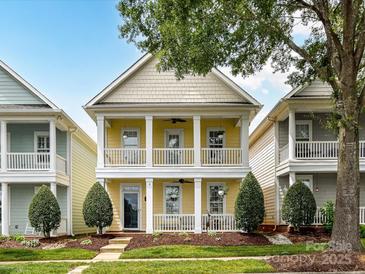 Charming two-story home with double porches, yellow siding, and manicured front yard landscaping at 2003 Trigger Dr, Indian Trail, NC 28079