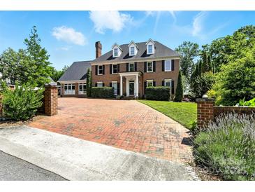 Stately brick home with mature landscaping, brick driveway, and classic black shutters under a sunny sky at 1009 13Th Avenue Nw Pl # 19, Hickory, NC 28601