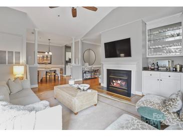 Open-concept living room with fireplace, built-in bar, and hardwood floors at 5730 Closeburn Rd # N, Charlotte, NC 28210