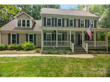 Charming two-story home with covered porch, blue shutters, landscaped yard, and American flag at 8300 Quarters Ln, Mint Hill, NC 28227