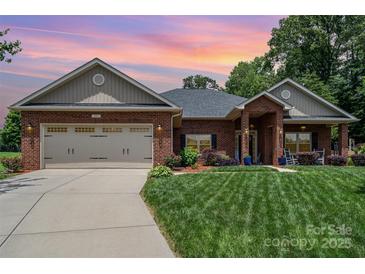Charming single-story brick home with a two-car garage, manicured lawn, and inviting front porch at 101 Harvest Farm Ct, Mount Holly, NC 28120