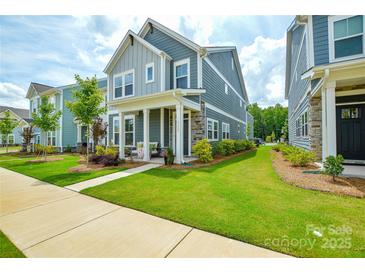 Beautiful two-story home features a well-manicured lawn and a charming front porch with stone accents at 10209 Mamillion Dr, Huntersville, NC 28078