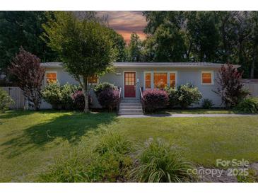 Charming single story home featuring a brick facade, well-manicured lawn, mature trees and a vibrant landscape at 1114 Urban Pl, Charlotte, NC 28209