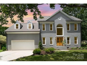 Charming two-story home with a well-maintained lawn, attached garage, and beautiful architectural details at 12411 Herdon Ct, Charlotte, NC 28277