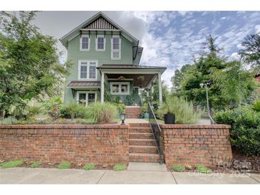 Charming two-story home with a brick facade, covered porch, and beautifully landscaped front yard at 1427 Main St, Charlotte, NC 28204