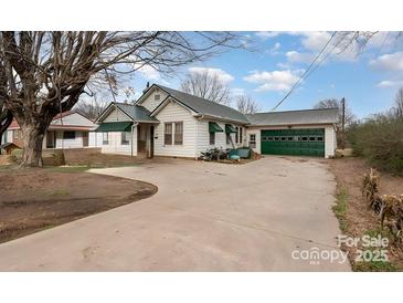 Charming home features a well-maintained exterior with a spacious driveway and a green garage door at 3220 Harmony Hwy, Harmony, NC 28634