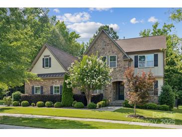 Charming stone home with a well-manicured lawn, blooming tree and lush landscaping at 11412 Preservation Ln, Charlotte, NC 28278