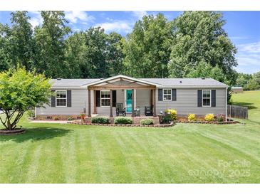 Charming single-story home features a covered porch, beautiful lawn, and mature trees in a serene setting at 1489 L R Schronce Ln, Iron Station, NC 28080