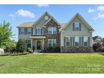 Inviting two-story home with a stone facade, gray siding, and well-manicured landscaping at 8427 Penton Pl, Harrisburg, NC 28075