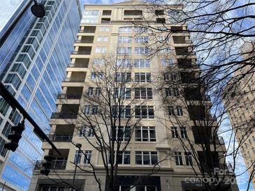Exterior shot of a tall beige apartment building with balconies next to a blue glass building in a city at 230 S Tryon St # 304, Charlotte, NC 28202