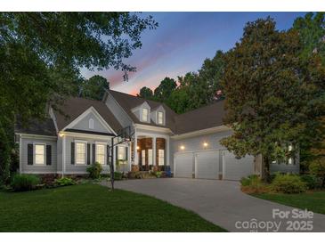 Charming home with a three-car garage, stone accents, and a basketball hoop on a well-manicured lawn at dusk at 4536 Rustling Woods Dr, Denver, NC 28037
