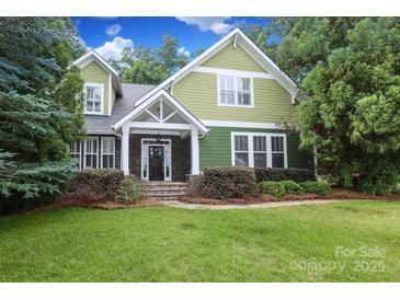Charming two-story green home with a stone-accented front porch and lush landscaping at 458 Leaf Arbor Ct, Clover, SC 29710