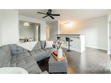 Bright living room with a ceiling fan, grey couch, dark floors, and a stylish breakfast bar at 1315 East Blvd # 327, Charlotte, NC 28203