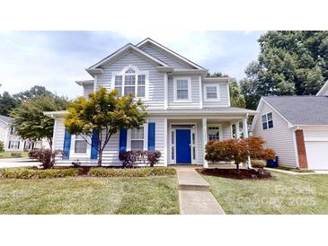 Charming two-story home featuring a blue front door, well-manicured lawn, and beautiful landscaping at 15280 Leslie Brook Rd, Huntersville, NC 28078