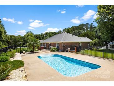 Backyard oasis featuring a sparkling pool, mature trees, and black aluminum fence at 1958 Cameron Heights Cir, Denver, NC 28037